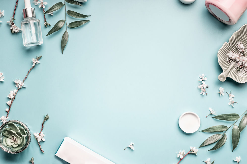 Beauty background with facial cosmetic products, leaves and cherry blossom on pastel blue