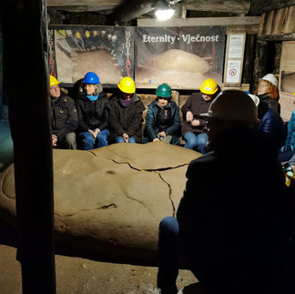 Mehrere 2 Besucher der Ravne Tunnelsysteme in Visoko erfühlen mit den Händen die Energie eines Megaliten