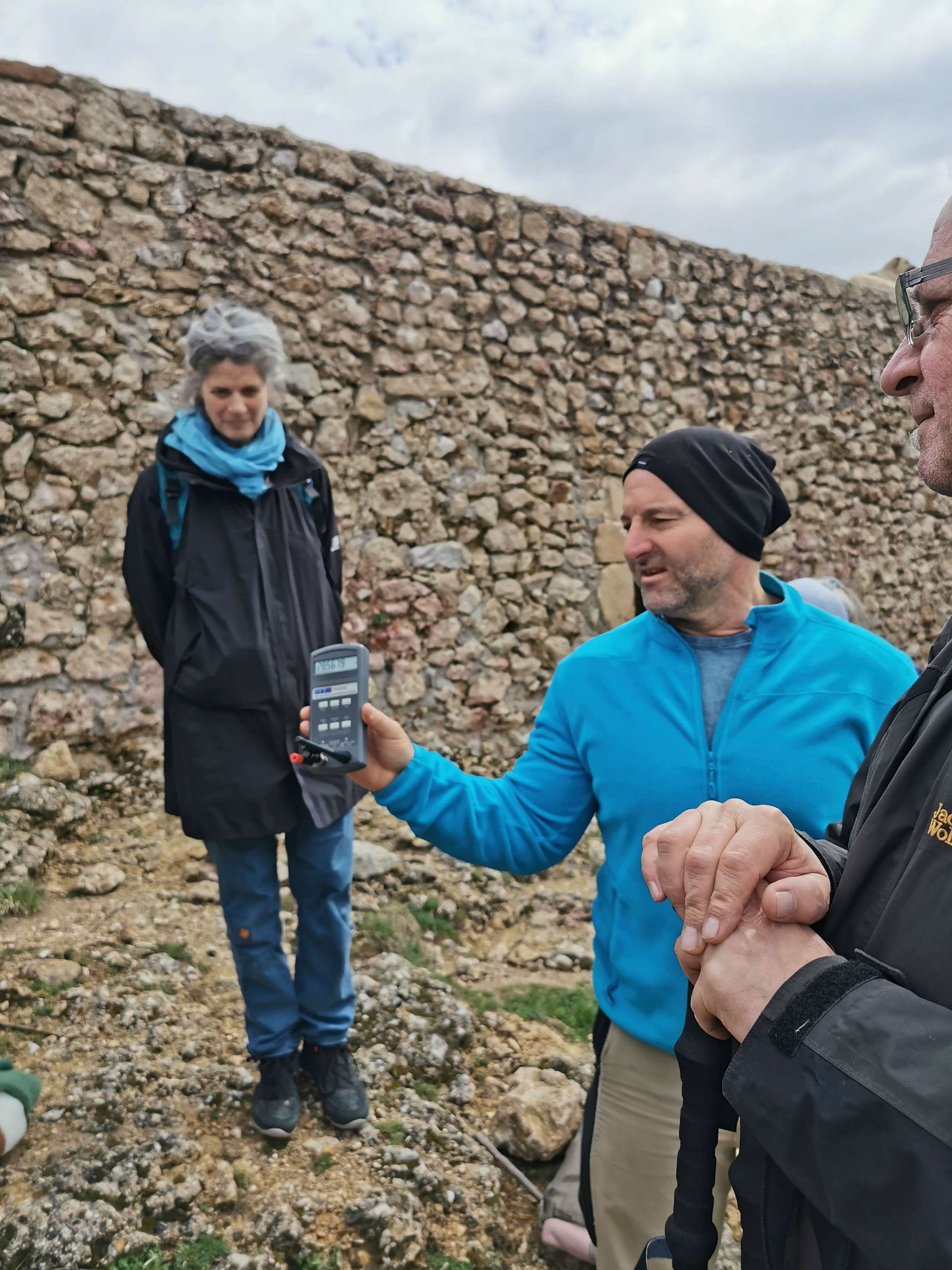 Stefan Paul Gruschwitz von Geoviva / Pyramide Lodge , der auf der Sonnen Pyramide in der Mitte einer Reisegruppe steht, ein Messgerät vorzeigt und etwas zu den angezeigten Messwerten erklärt