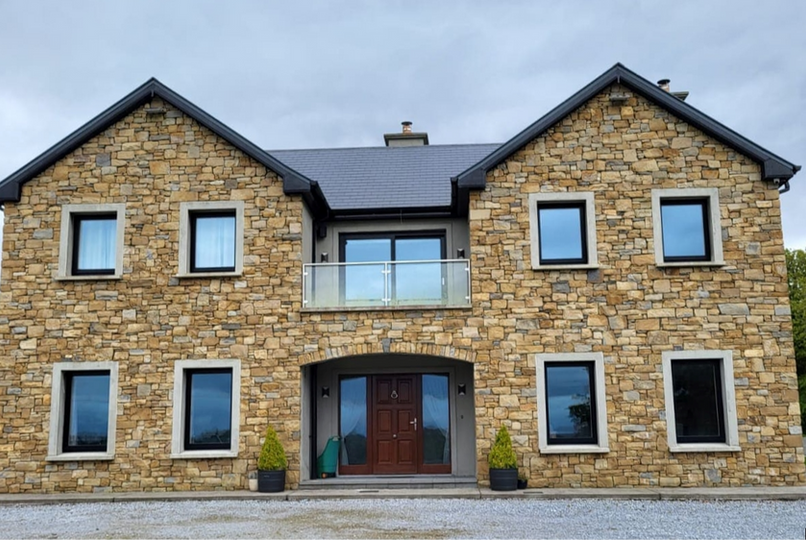 Large stone house with dark roof and balcony