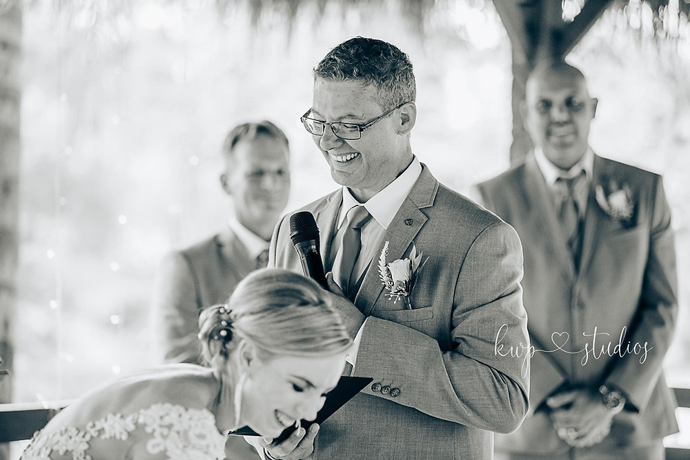 Bride hysterically laughing while groom says his vows with a smile on his face