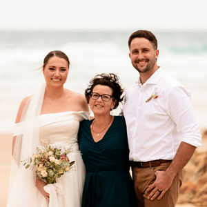 A wedding couple standing with their celebrant Kerri Watkins at Honeymoon Bay on Moreton Island