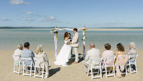 couple standing in front of arbour at Reeders Point, Kooringal on Moreton Island in front of just their parents, nannas and sister