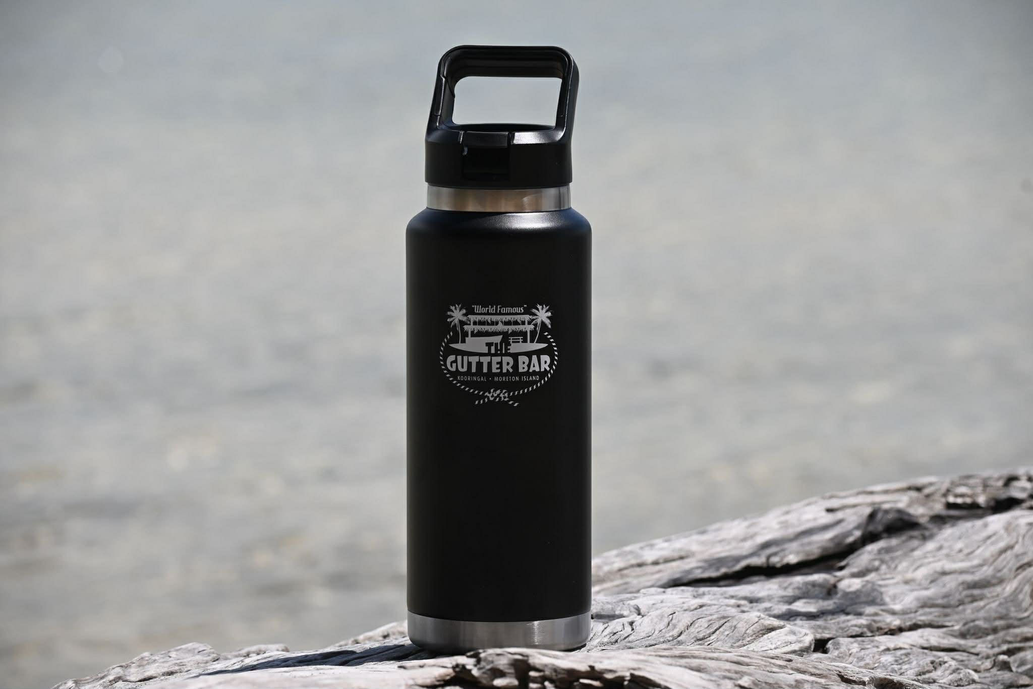 The Gutter Bar black insulated water bottle on the beach