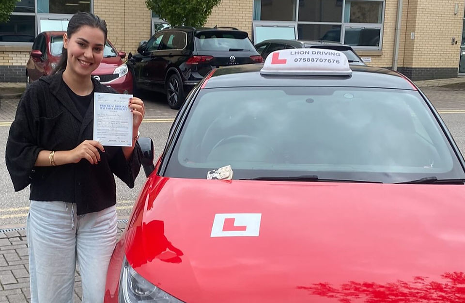 Young woman with driving certificate next to red L-plate car