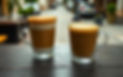 2 coffee cups on a dark natural wooden table, with a quiant street in the background.jpg