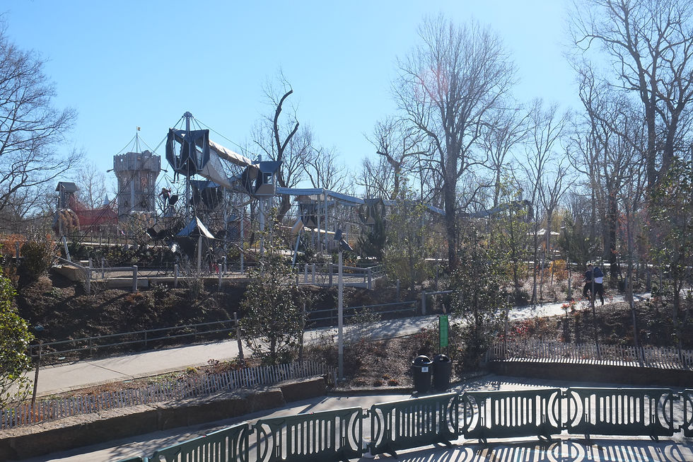 Climbing towers and rope bridges surrounded by trees, paths, and benches at Gathering Place in Tulsa.