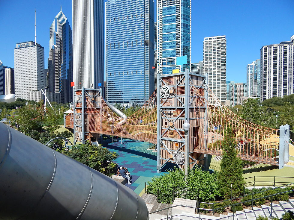 Play towers, rope bridges, slides, and planting at Maggie Daley Park in Chicago, with the city skyline behind.