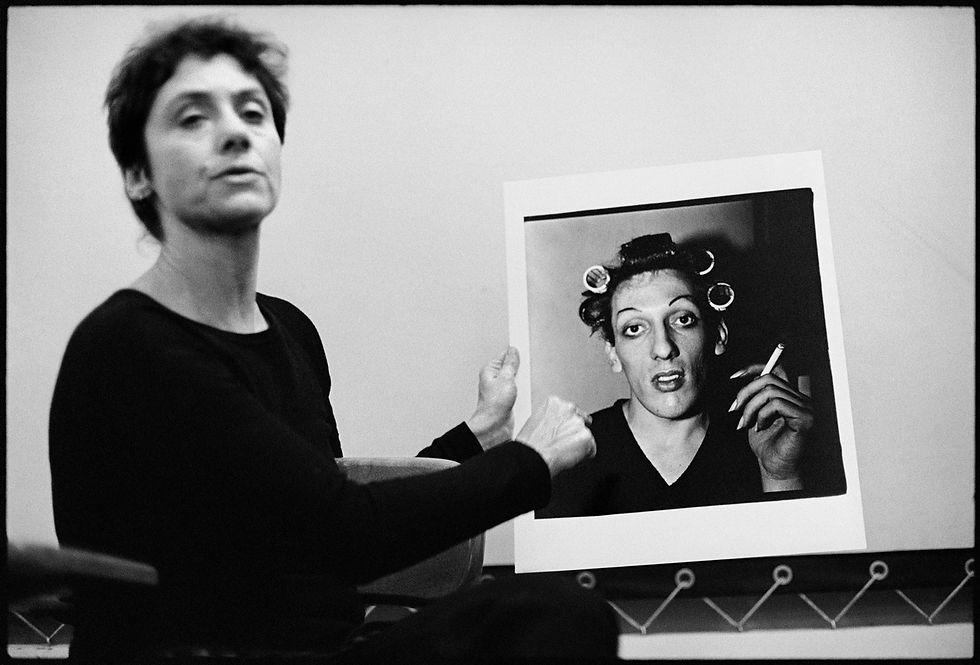Diane Arbus holding her photograph of a young man in curlers.