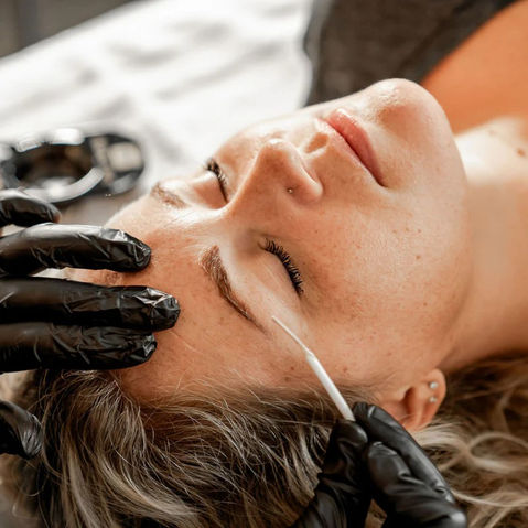Brow specialist at Lavoom Salon in Calgary applying brow tint and shaping the brows during a design and tint service.