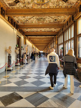 people walking through a museum with intricate and ornate ceiling