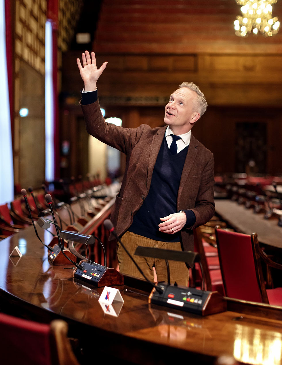 Henrik Nerlund pekar med handen mot väggarna i Rådssalen.