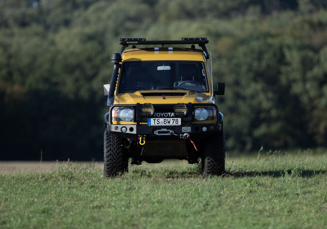 Gelber Geländewagen fährt über Wiese