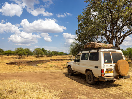 White Land Cruiser parked in savannah of Uganda