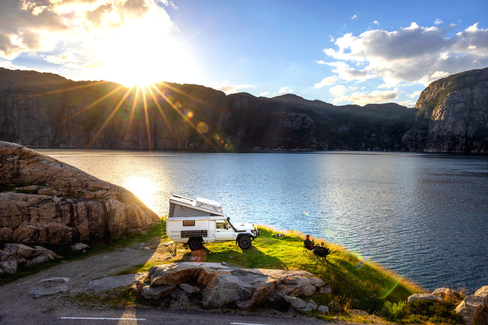 Weißer Campervan am See bei Sonnenuntergang