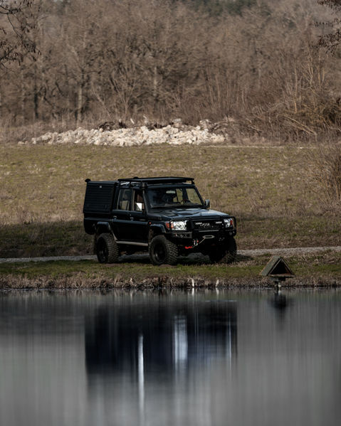 Schwarzer Geländewagen an einem See, robustes Fahrzeug