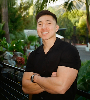 man standing with arms crossed in front of trees