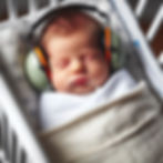 Baby wearing ear protection as it sleeps