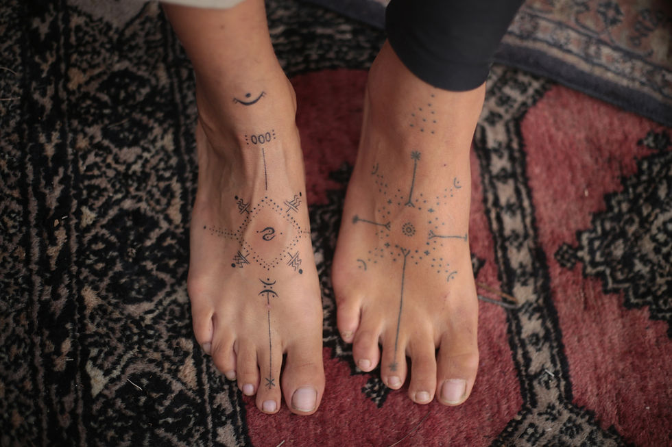 Close-up of two girls’ feet displaying delicate handpoke tattoos, showcasing minimalist and natural body art.