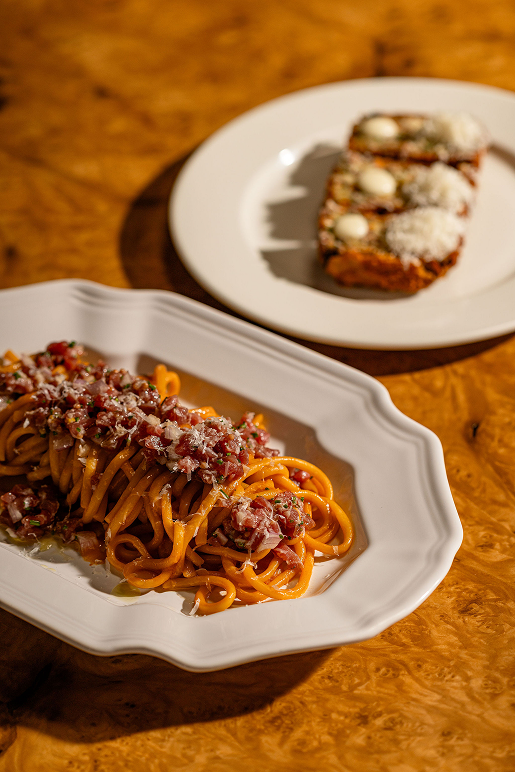 Pasta with a crumble topping and toast on a wooden table