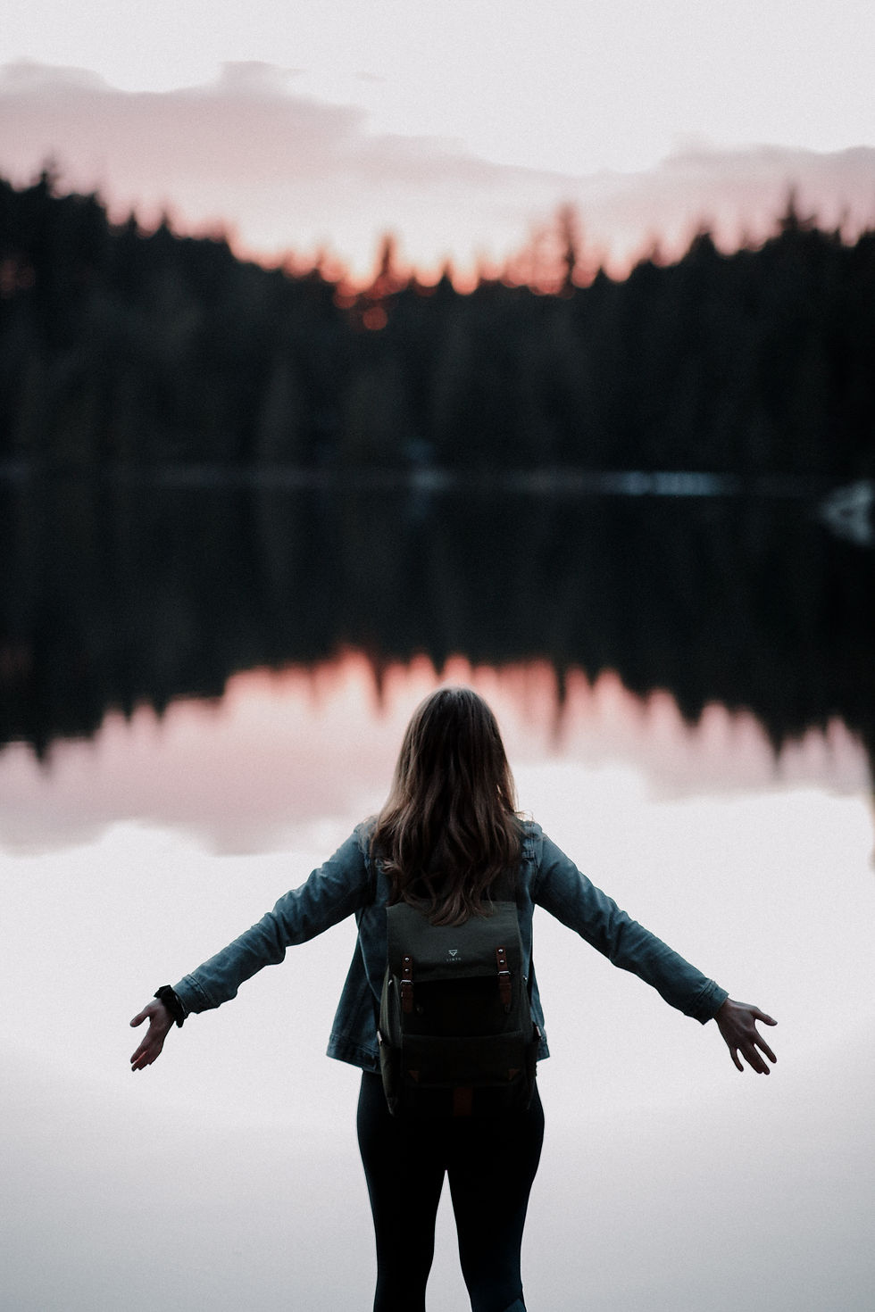 a woman standing in front of a lake at dusk with her arms stretched out, holistic healing, therapy in st petersburg fl
