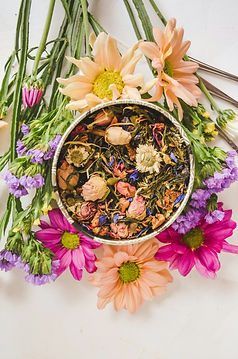 a bowl of dried flowers sitting on top of a bouquet of fresh flowers, herbal remedies, holistic therapy