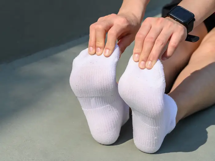 Touching toes, heel pain, plantar fascia, calf stretching, white socks, seated forward bend