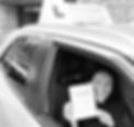 A learner driving in her instructors car showing her test pass certificate