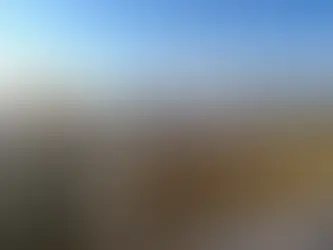 Paysage du Jura enneigé sous un ciel bleu, collines et forêts hivernales baignées de soleil, ambiance calme et nature préservée.