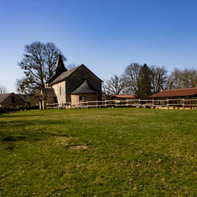 Église du Prieuré de Soudaine-Lavinadière en Corrèze, architecture médiévale en pierre entourée d'un jardin herbeux