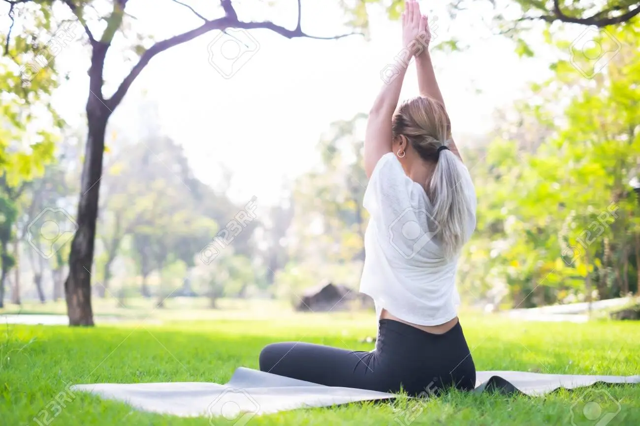 141389458-portrait-of-young-woman-practicing-yoga-in-garden-female-happiness-blurred-backg
