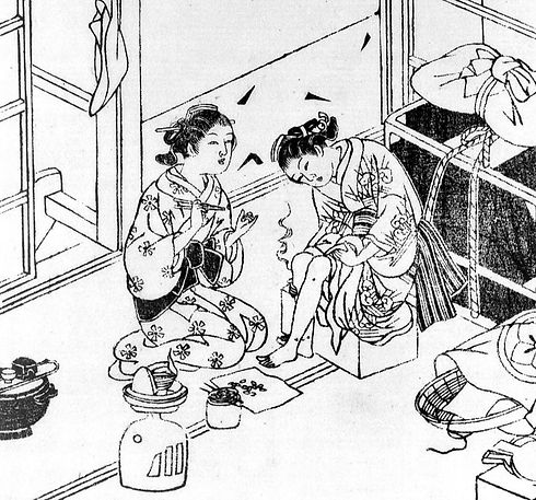 Moxa treatment- a young woman kneels and applies moxa (a smouldering blend of medicinal pl
