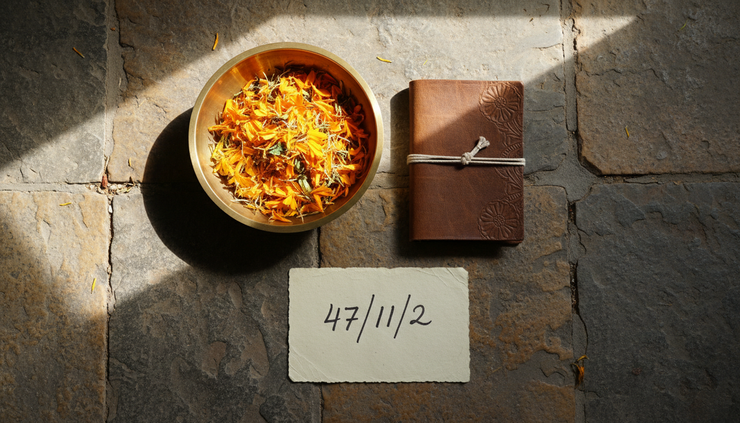 Top-down view of a brass bowl, a notebook, and the number 47 written on paper