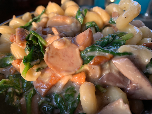 A bowl full of creamy wild mushroom pasta and basil