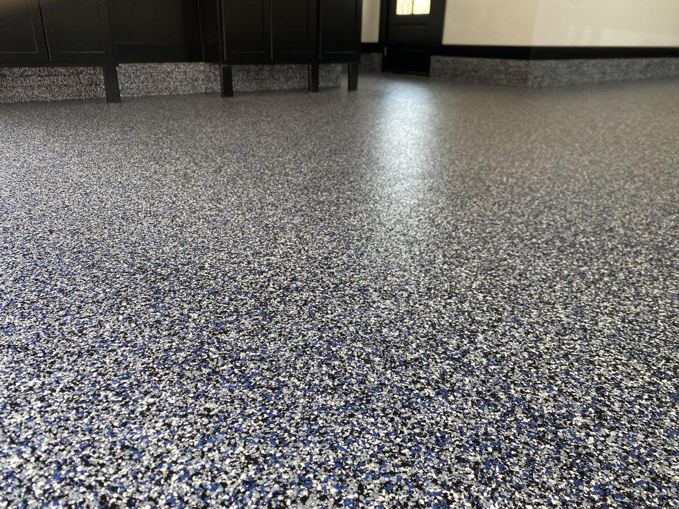 Close-up view of blue, black, and white decorative flake polyurea concrete floor coating installed by Armor Shield Concrete Coatings.