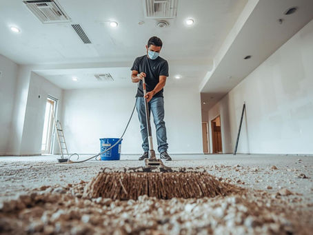 Worker sweeps post-construction debris during interior cleanup
