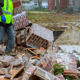Worker stands beside piles of brick and concrete demolition rubble