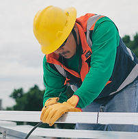 A man with a hard hat looking down as he works on a metal structure.