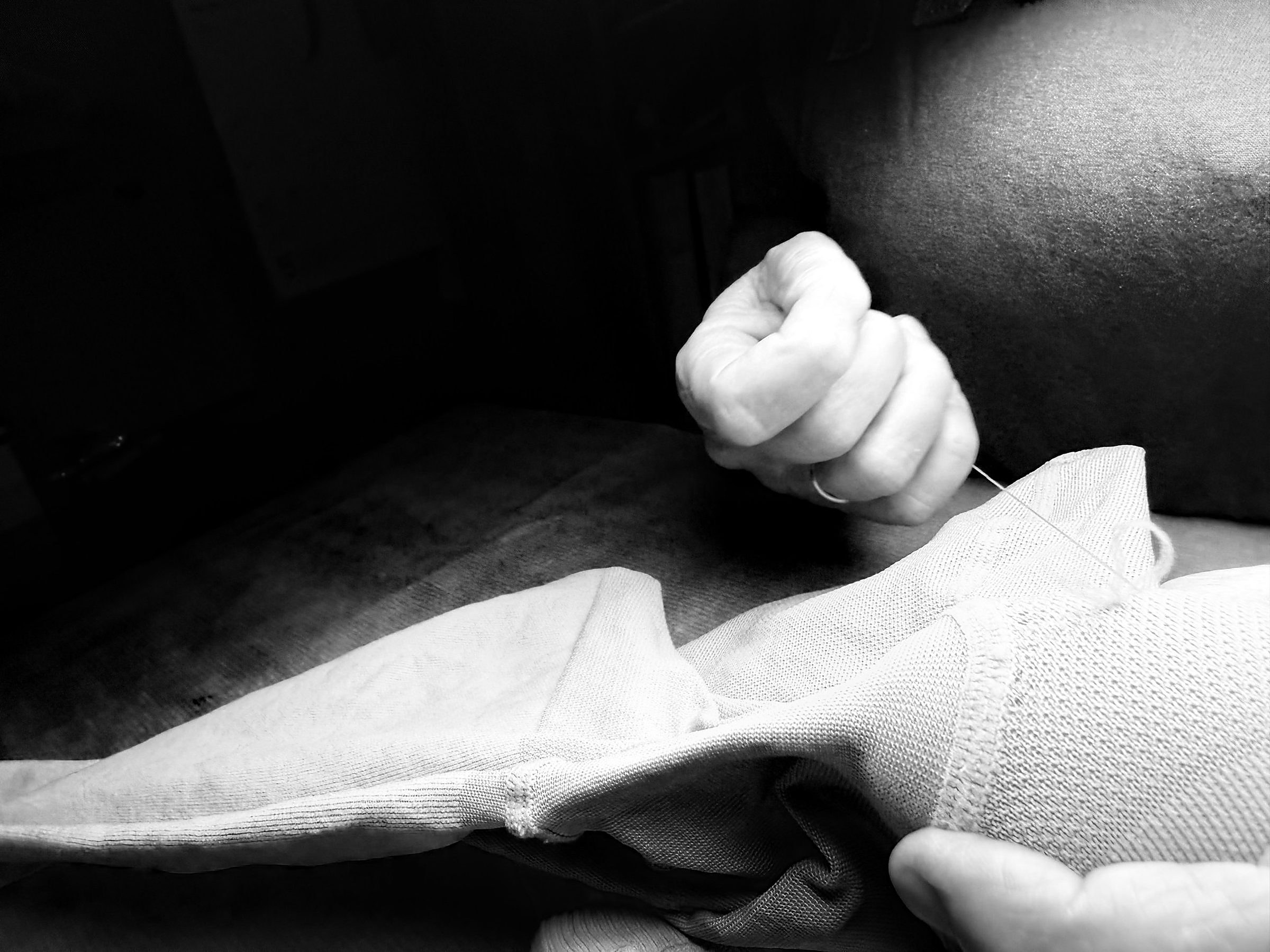 La main de Marika tient l'aiguille au-dessus d'un bas de contention en cours de remaillage