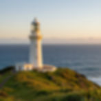 White lighthouse on a grassy cliff by the ocean