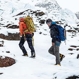Two climbers walking up the mountain on a snowy rock field