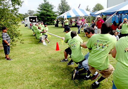 Coworkers playing tug‑of‑war during an outdoor Picnic Master company event.