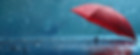 Red umbrella lying open on the ground with rain falling.