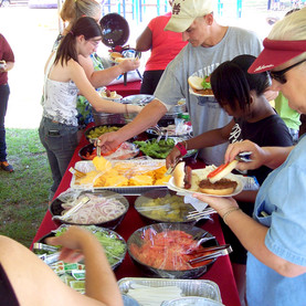 Employees serving themselves from catering dishes on a buffet table at a Picnic Master event.