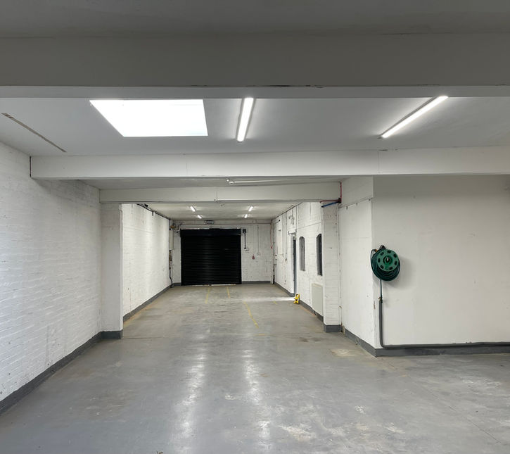 Empty white walled room that narrows into a corridor