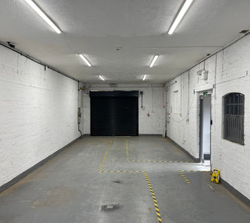 End of the corridor with white walls a black door space at the end and a door and window on the right wall