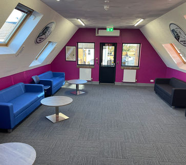 refurbished office space, with sloped walls on either side, Everyone's Gang logos on each of these walls
