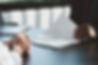 Person with hands together in fron of clipboard with document on