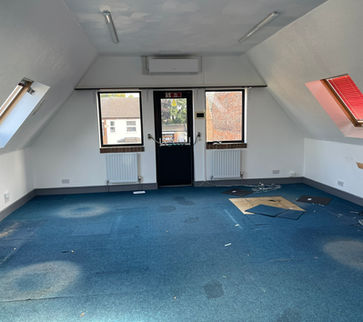 run down office space, with sloped walls on both sides, and old blue carpets