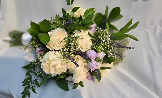 White roses and lavender bridal bouquet on white silk.